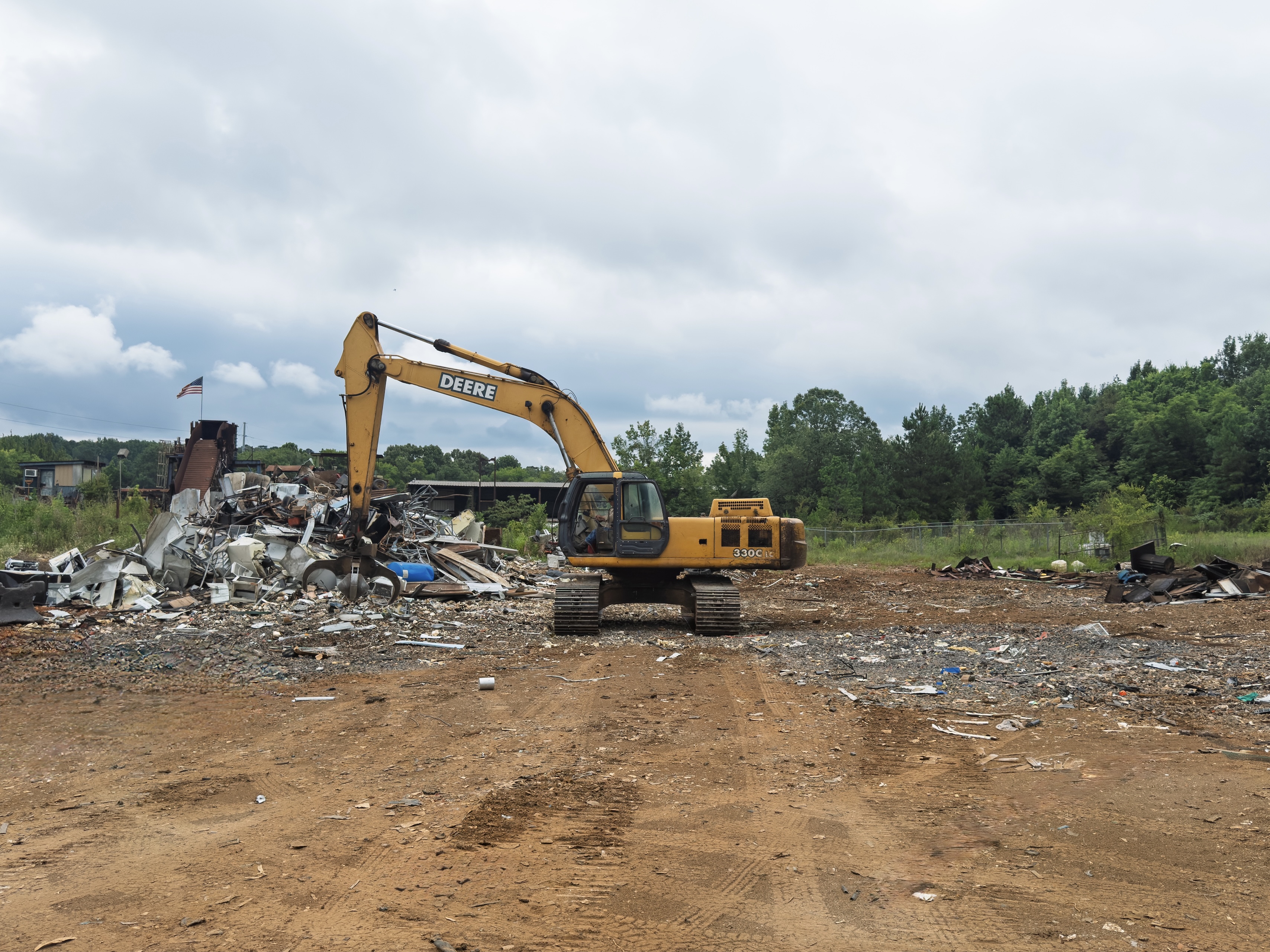 man in heavy equipment moving scrap between scrap piles